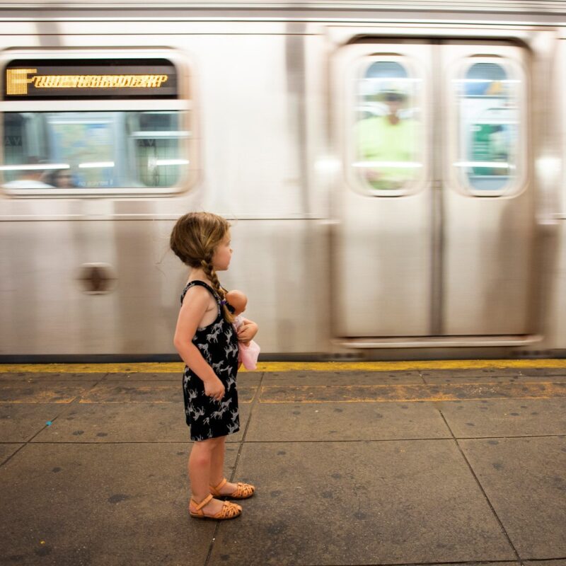 girl with doll riding subway