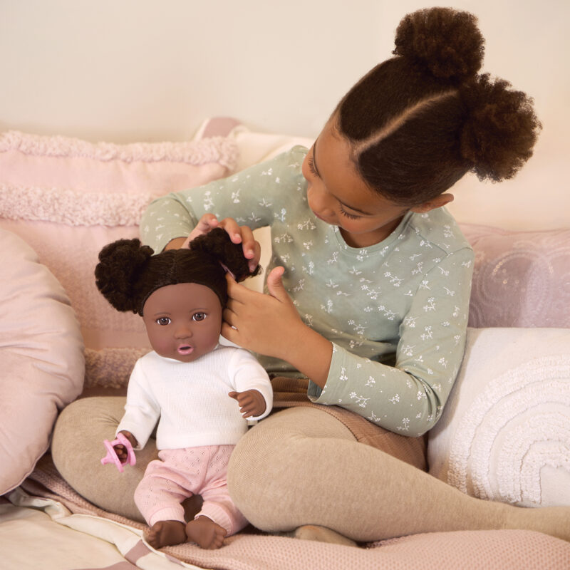 girl brushing lullababy doll's curly dark brown hair