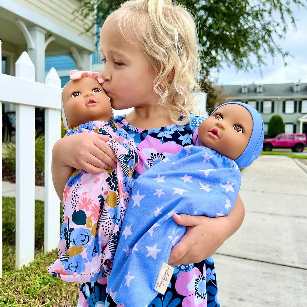 girl and lullababy dolls, outdoors in the sun, kissing baby dolls